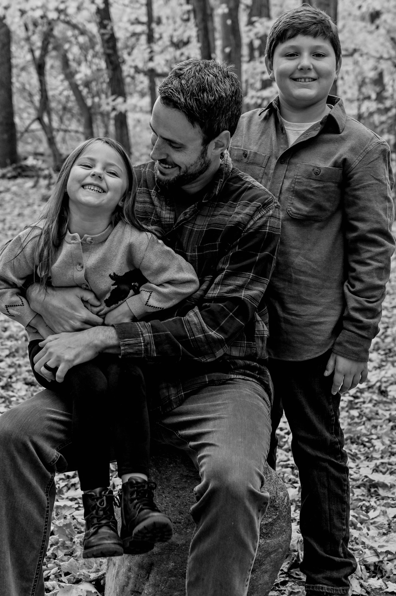 Black and white photo of family members laughing and embracing outdoors.