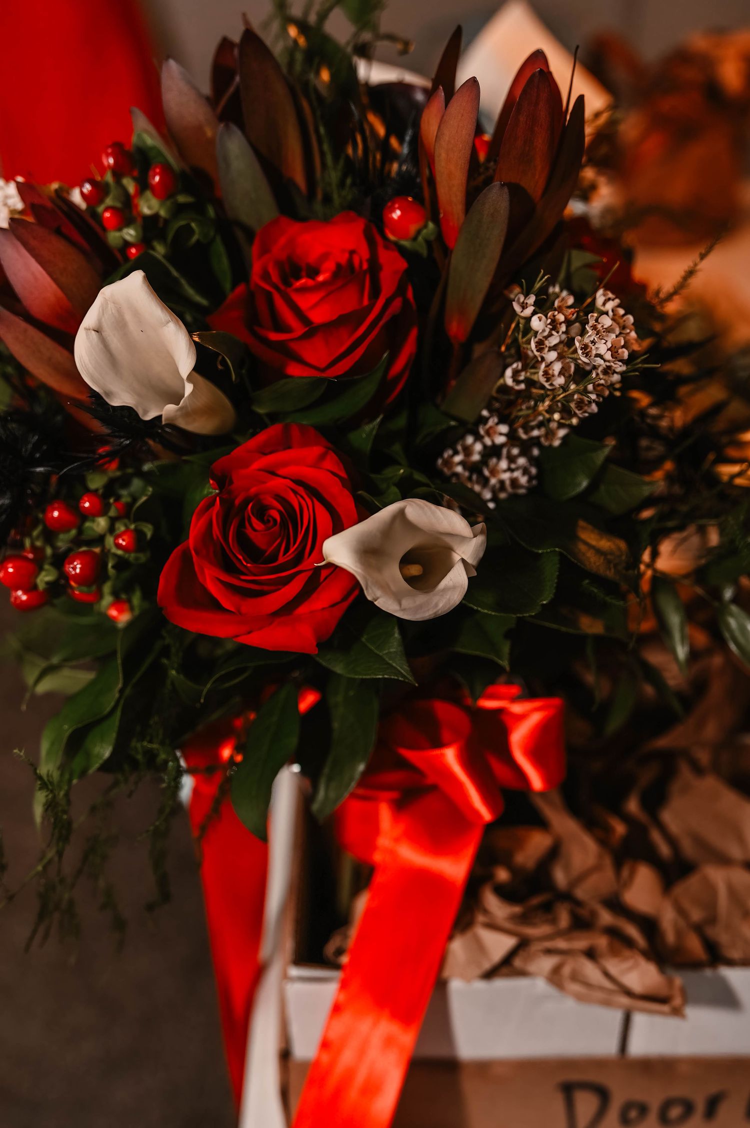 Elegant red rose bouquet with white accents tied with red ribbon.