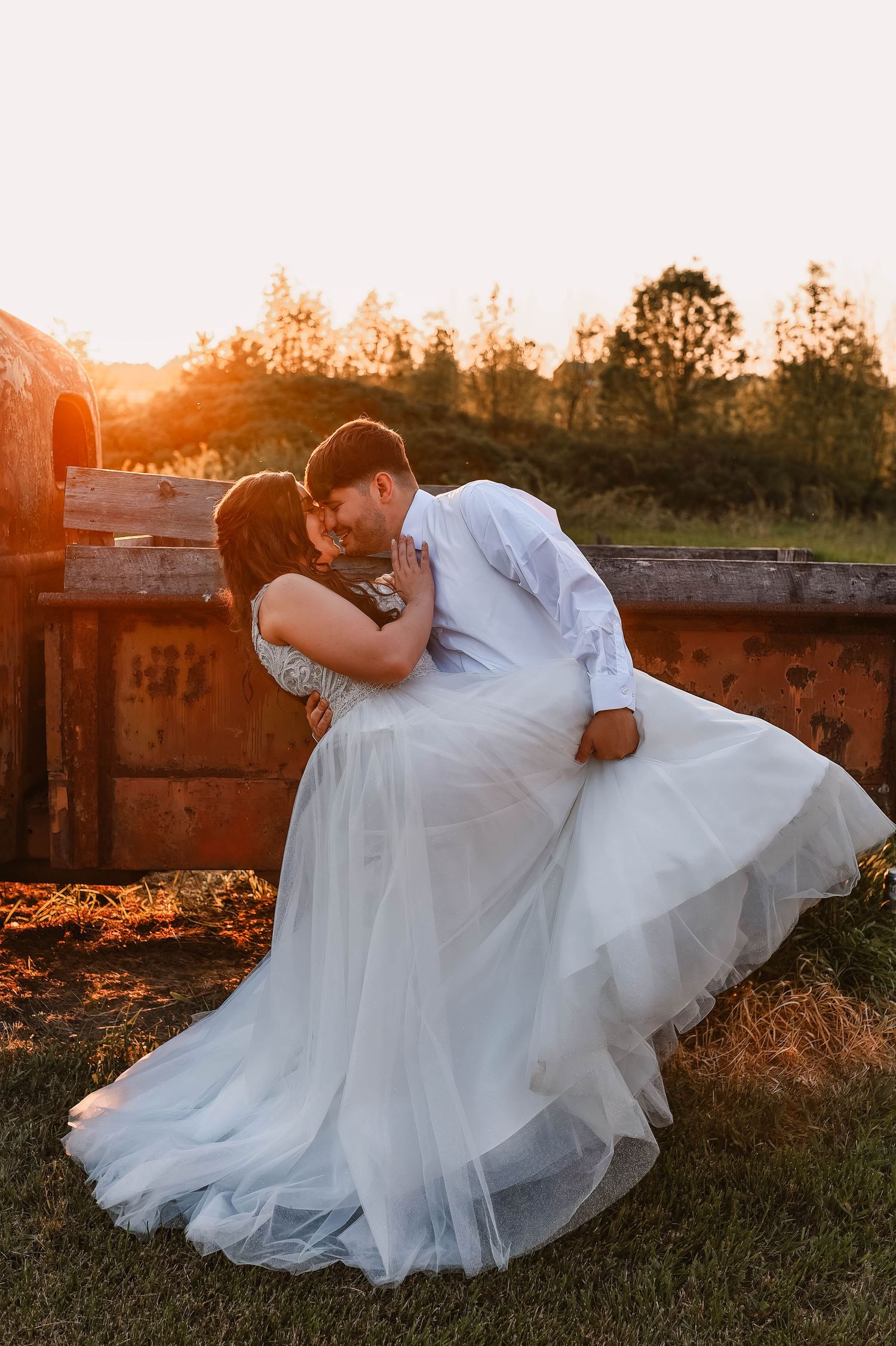 Romantic sunset photos of a couple in wedding attire laying in grass during golden hour.