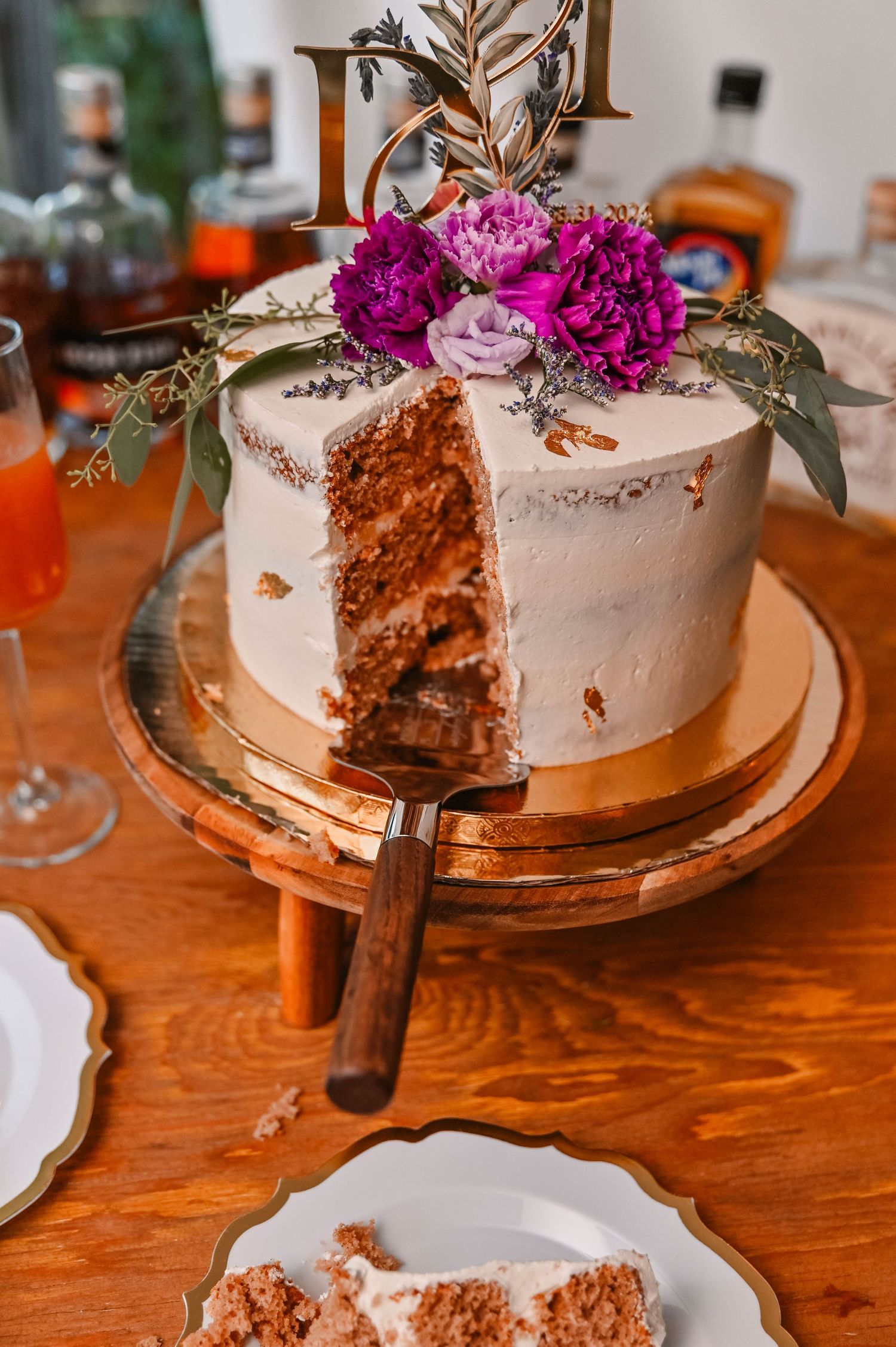 A white wedding cake with pink flowers and a slice removed showing layers inside.