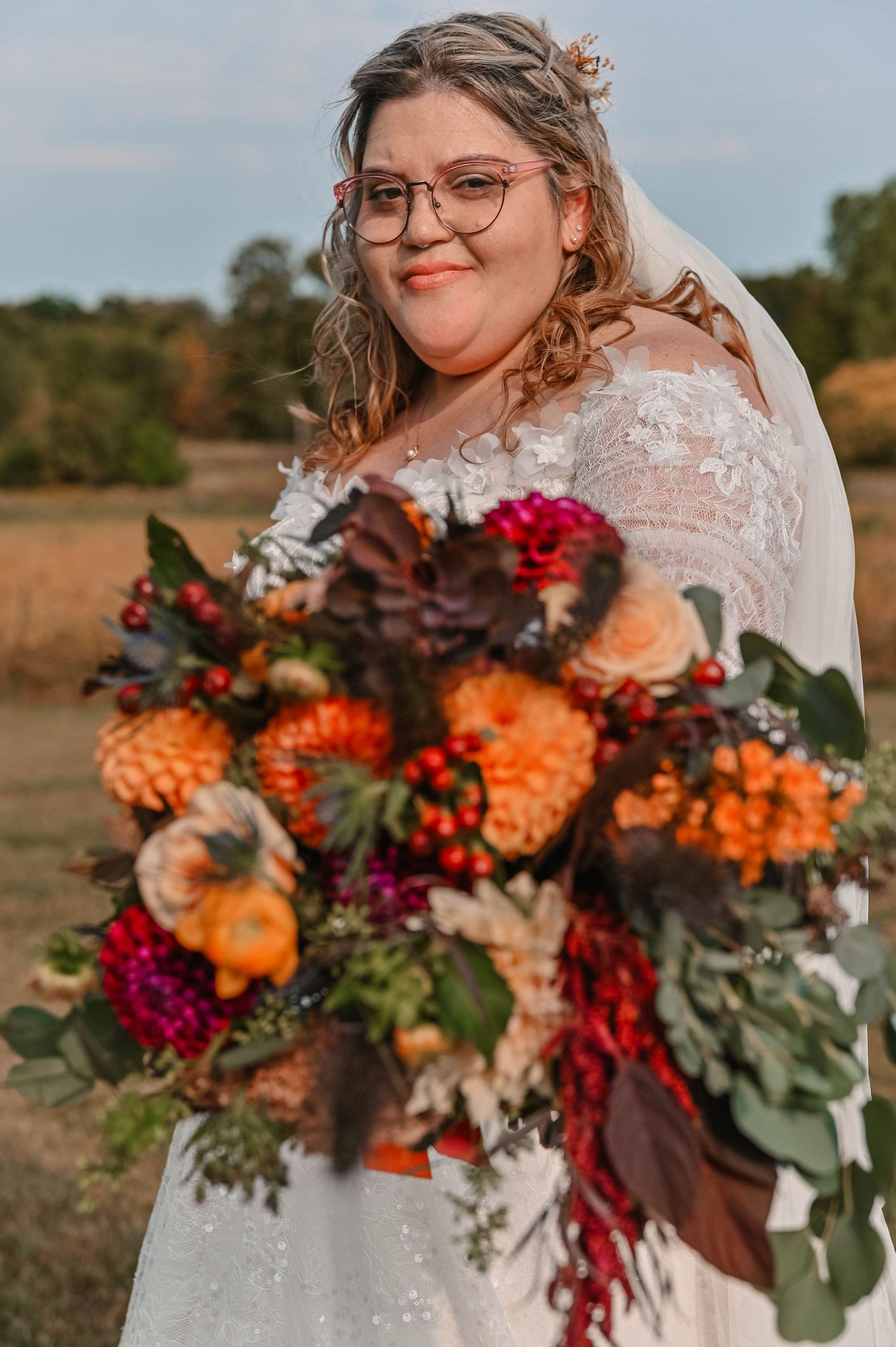 Vibrant autumn bridal bouquet featuring orange, burgundy and red flowers with eucalyptus leaves.