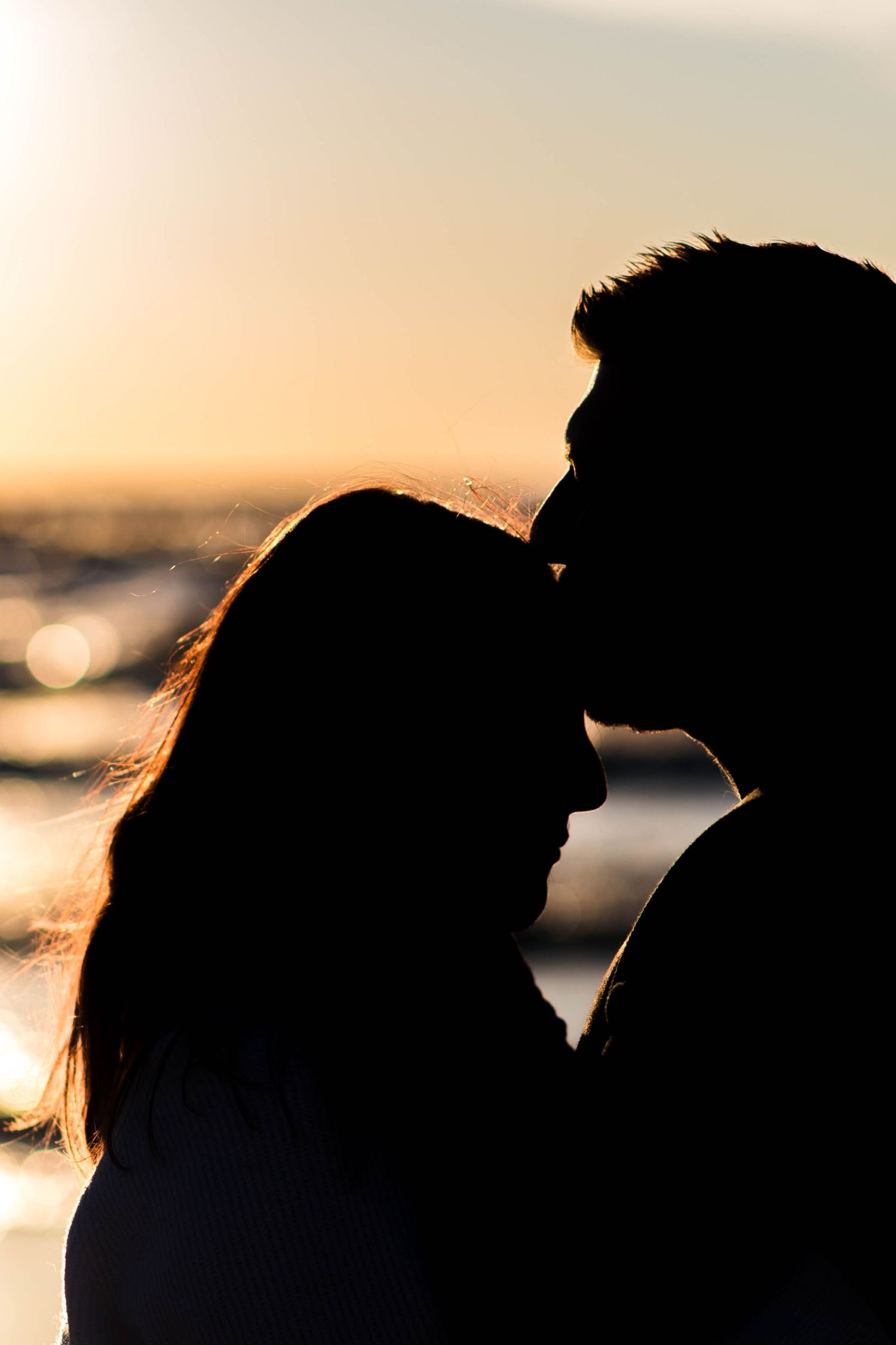 Silhouette of couple against sunset sky by the ocean.