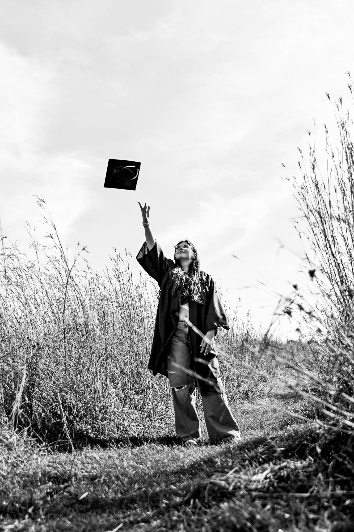 Black and white graduation photos capturing cap toss moments in a natural setting.