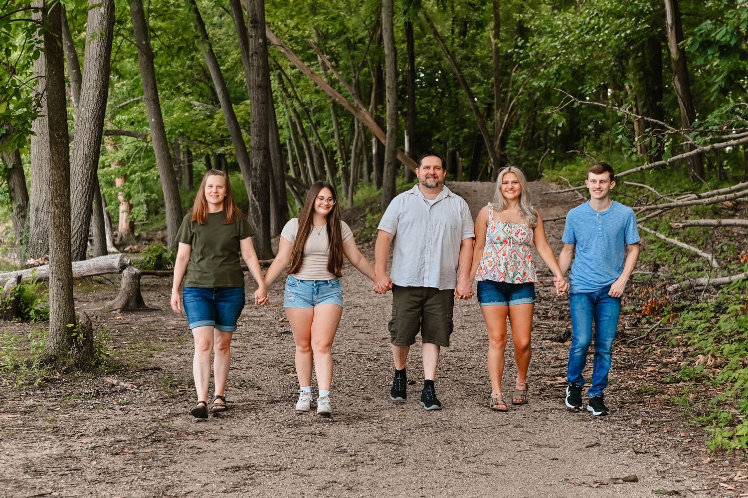 People walking together on a wooded trail during a summer day.