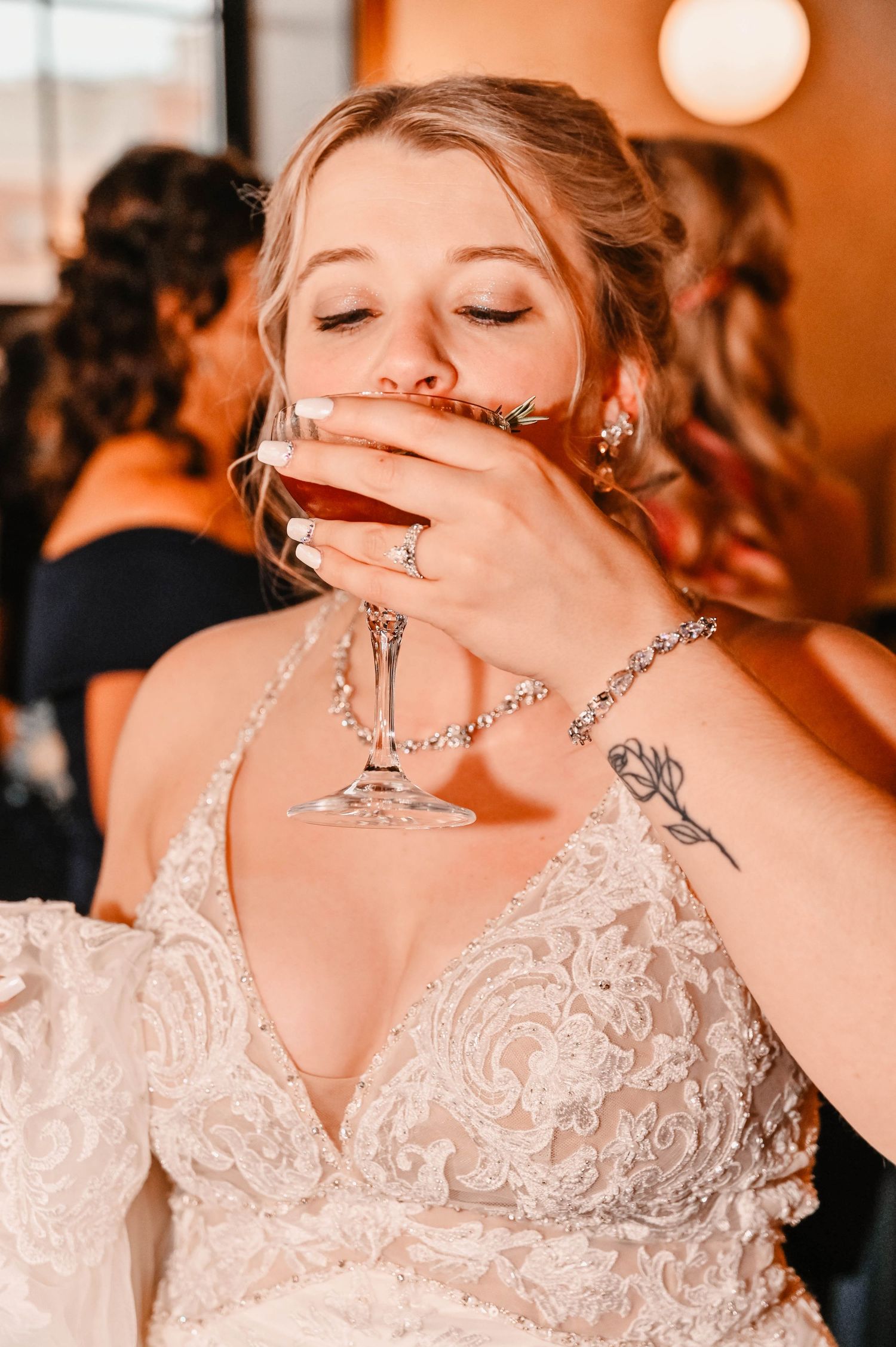 Bride in lace wedding dress holding necklace pendant.