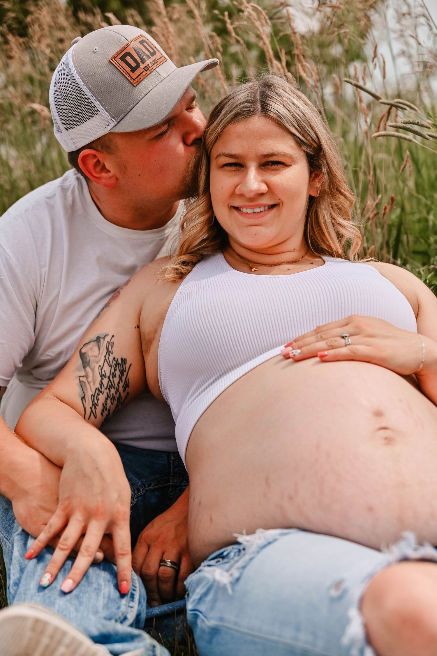 Intimate maternity photos of a couple sharing tender moments in a natural outdoor setting.