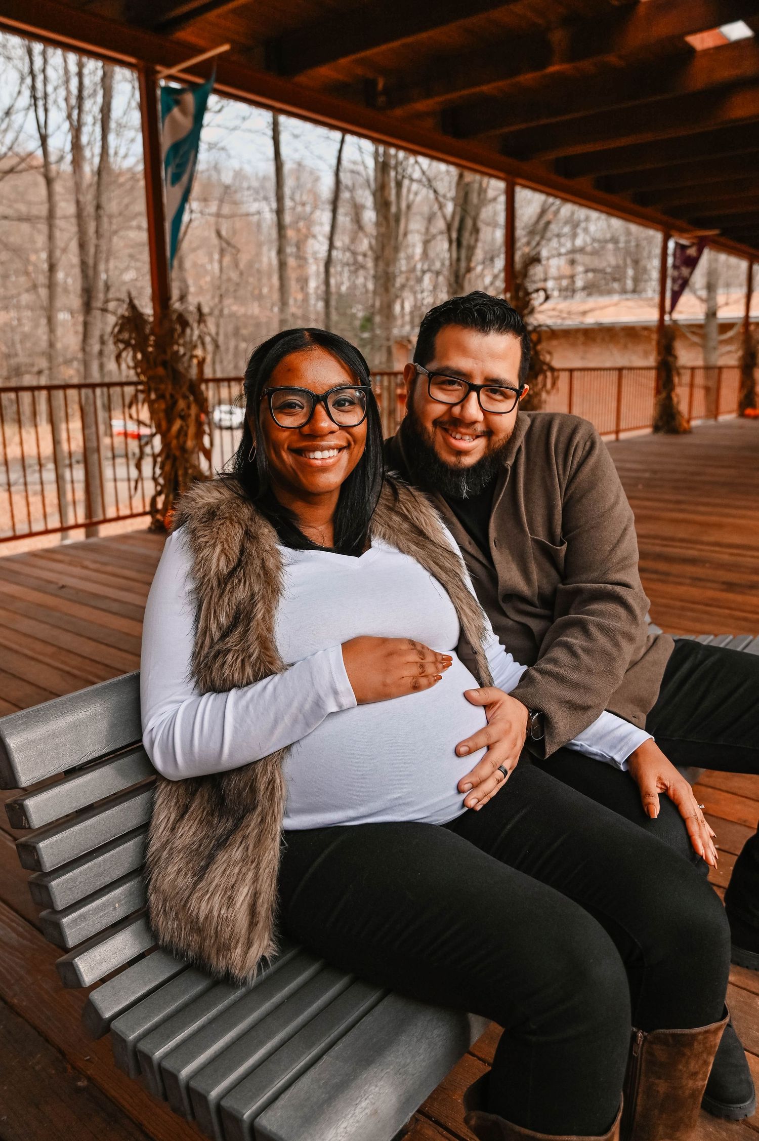 A couple shares laughter while sitting together on a wooden bench outdoors.
