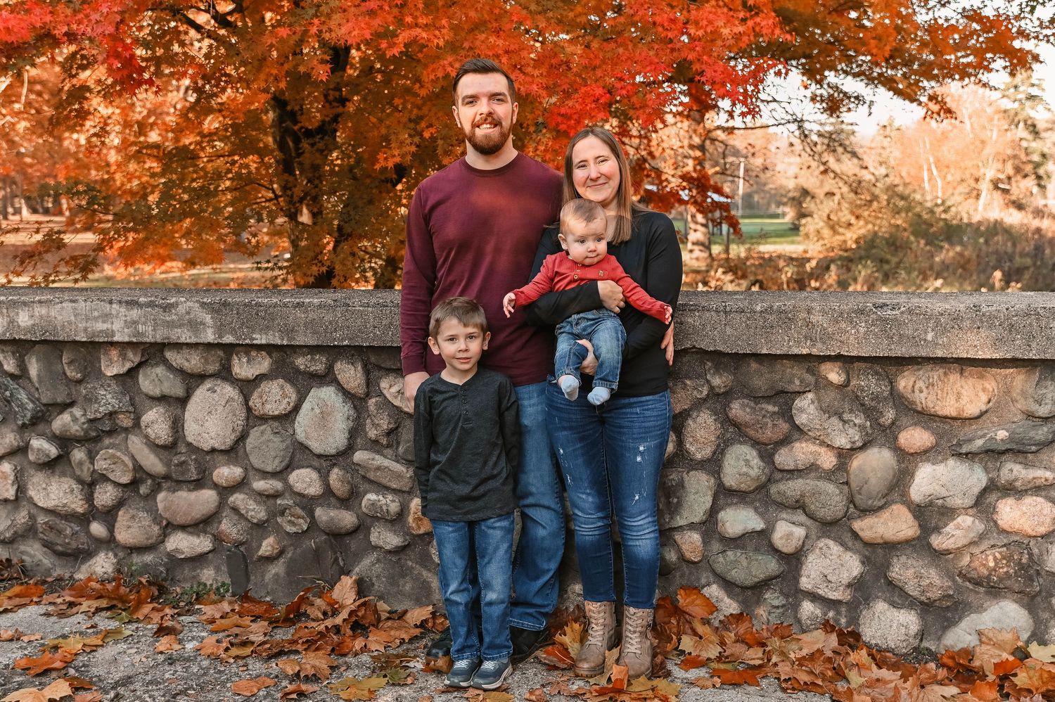 Family photos taken against a rustic stone wall with fall colors in the background.