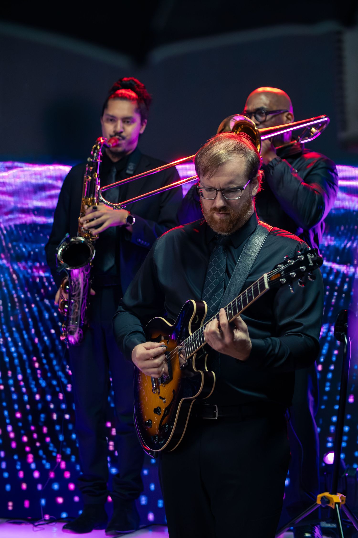 Musicians play guitars against a backdrop of blue LED lights during a live performance.