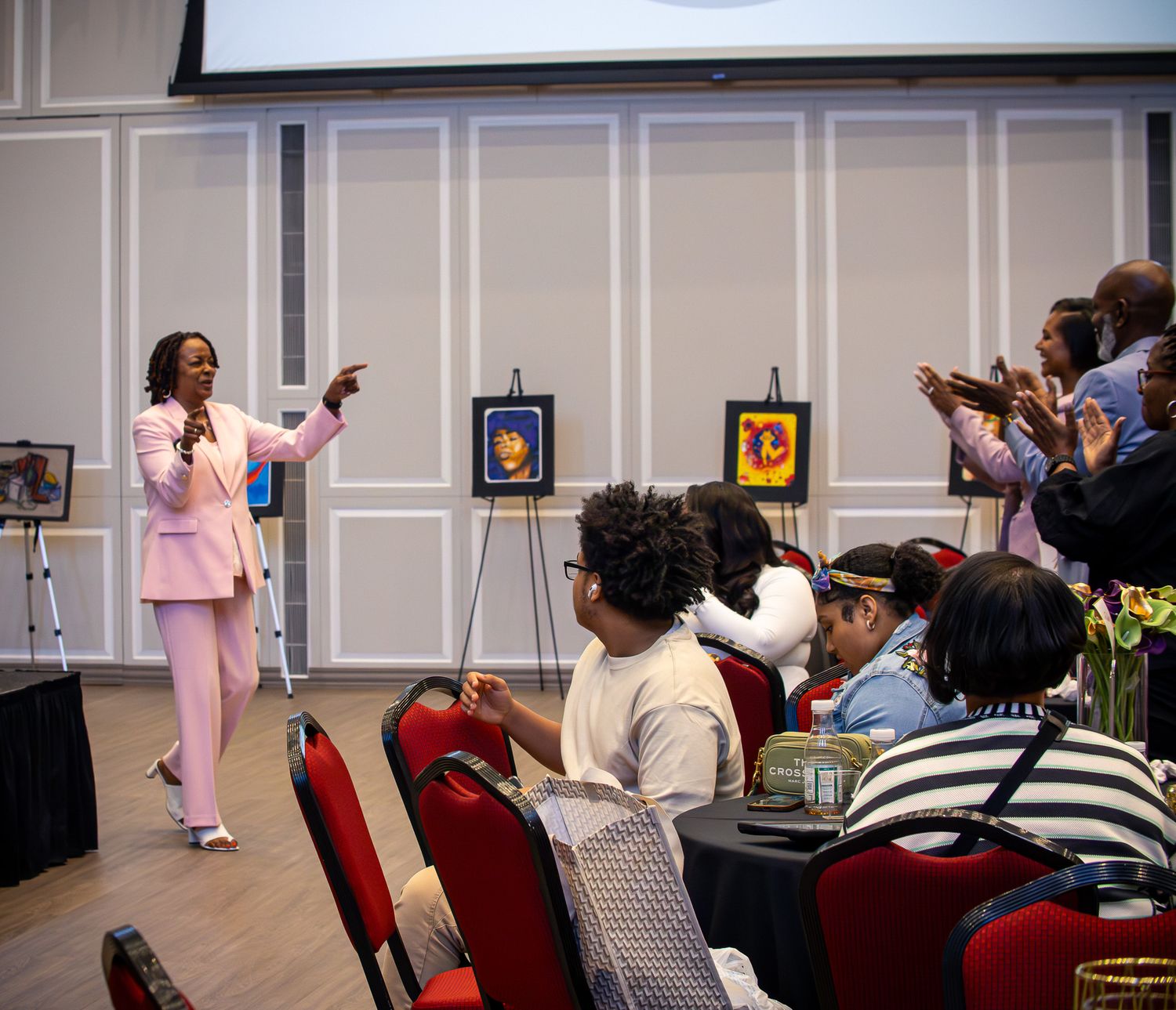 Woman in pink suit presenting awards to audience at University of Maryland event.