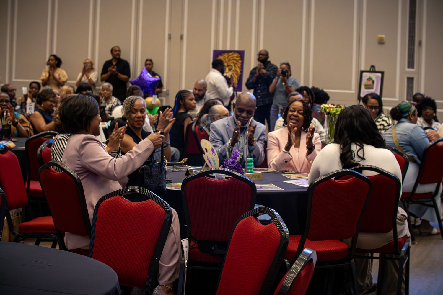 Diverse group of people networking at a formal banquet event, seated at round tables in a large conference hall.