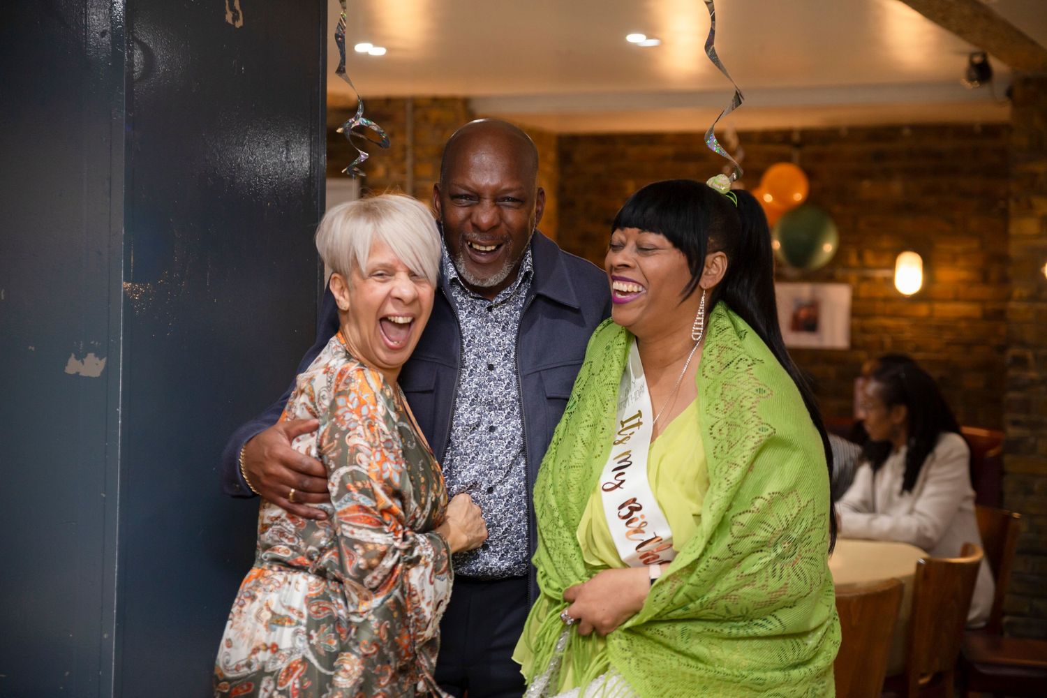 Group celebrating and laughing together in a cozy restaurant setting.