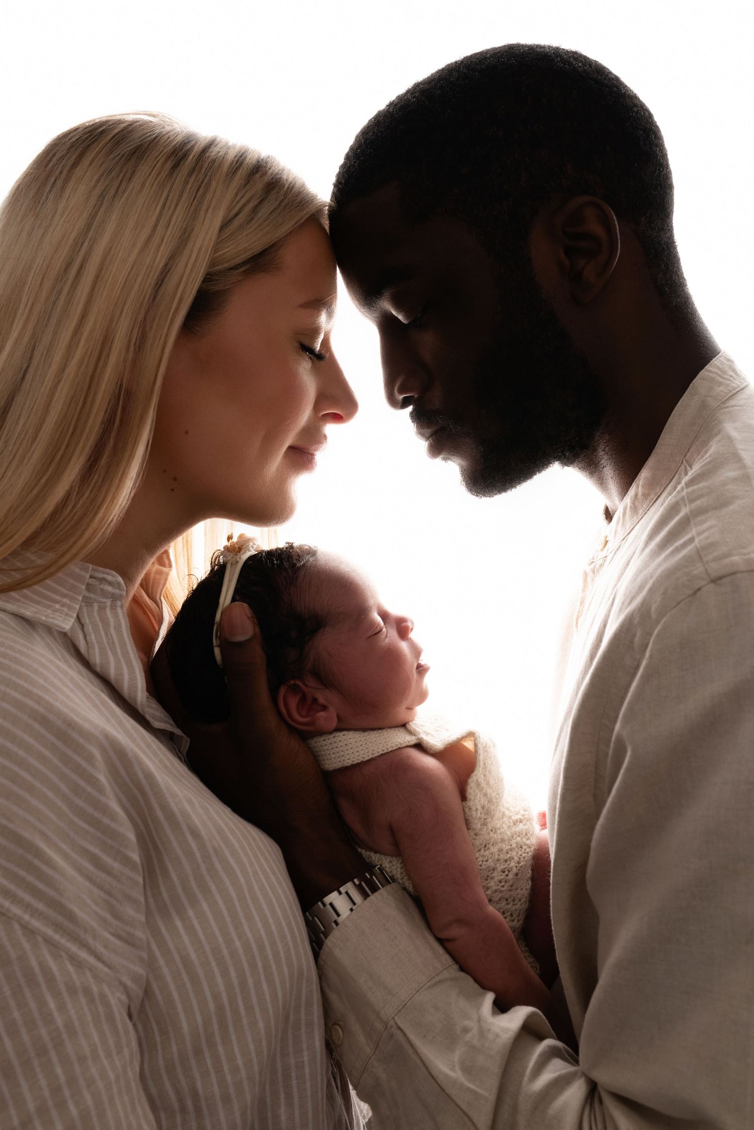 A series of intimate silhouette portraits showing tender moments between a couple and their newborn baby.