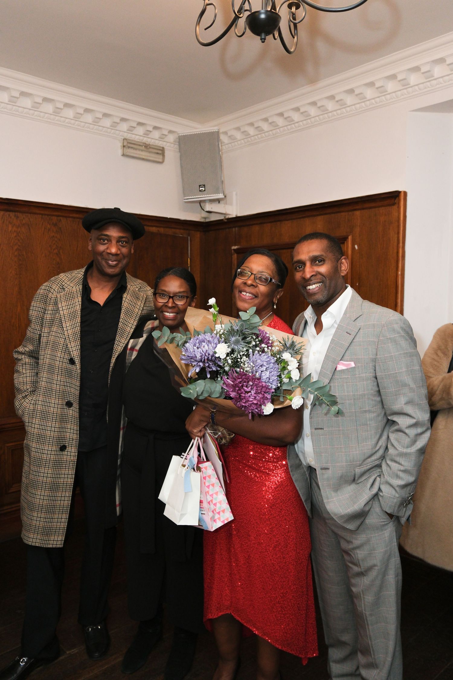 Celebration gathering with people in formal attire and floral bouquets in an elegant indoor setting.