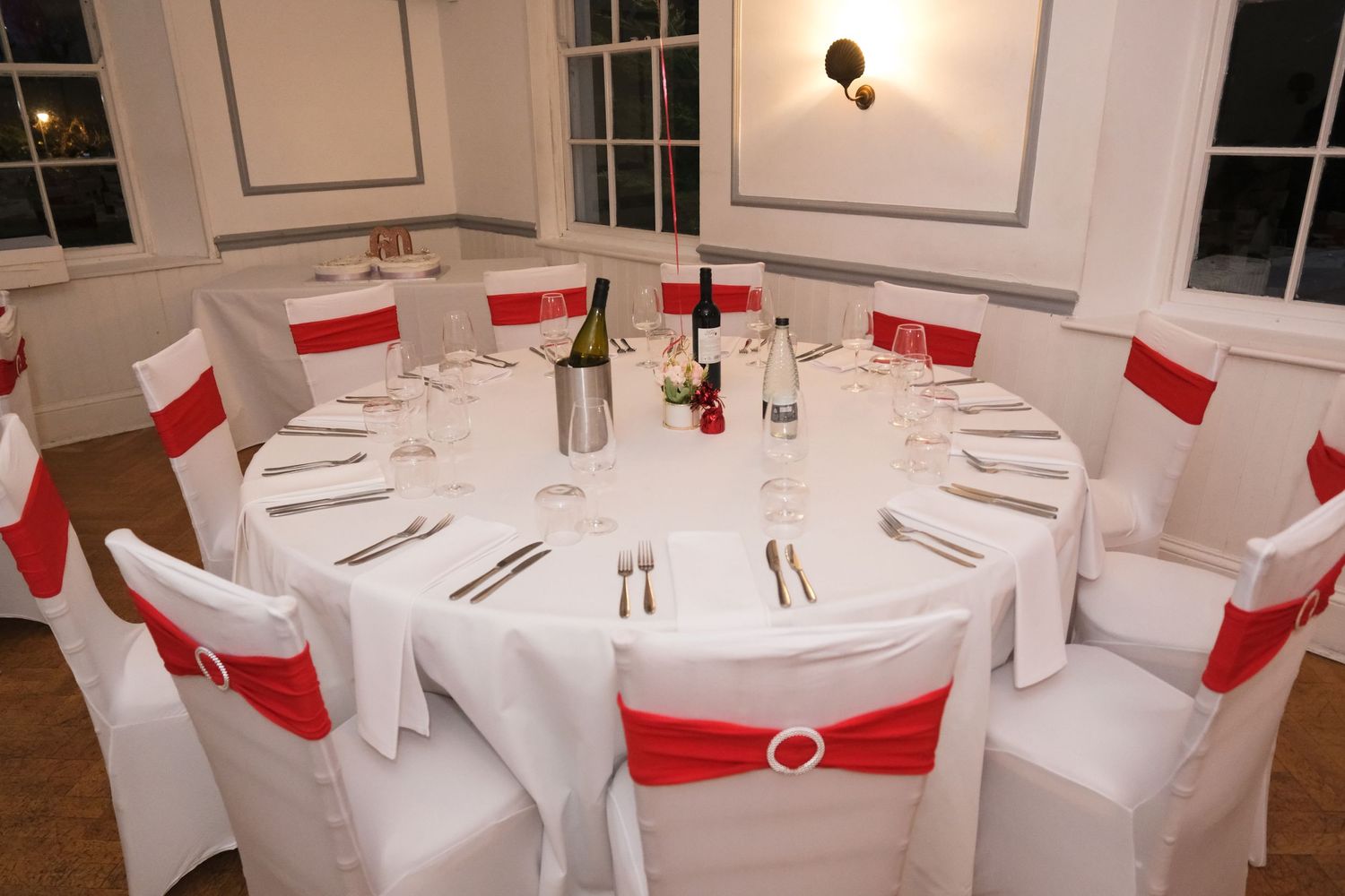 Elegant white dining tables with red accents set up for a formal event.