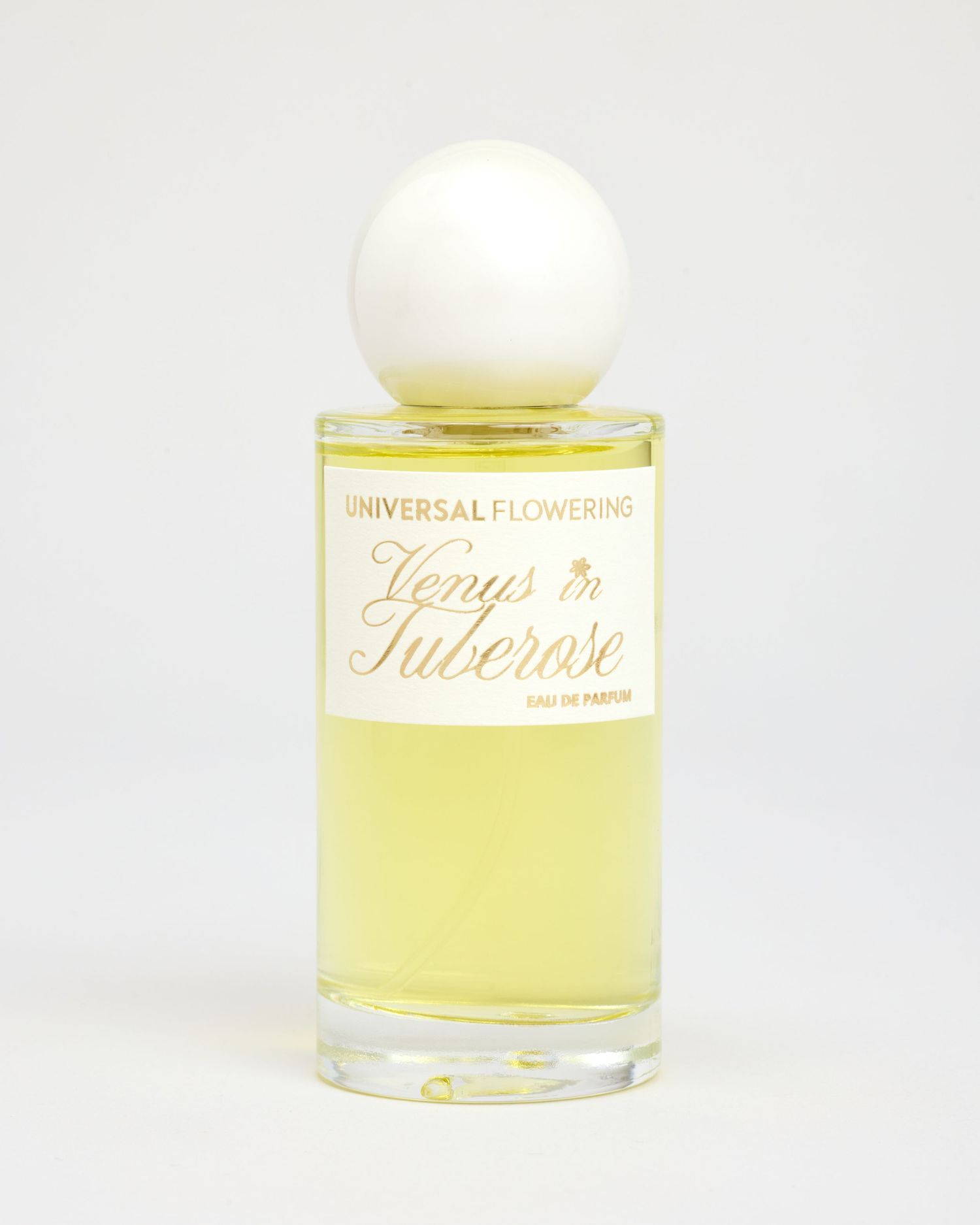 A bottle of Universal Flowering's fragrance Venus in Tuberose sits on a light grey backdrop.