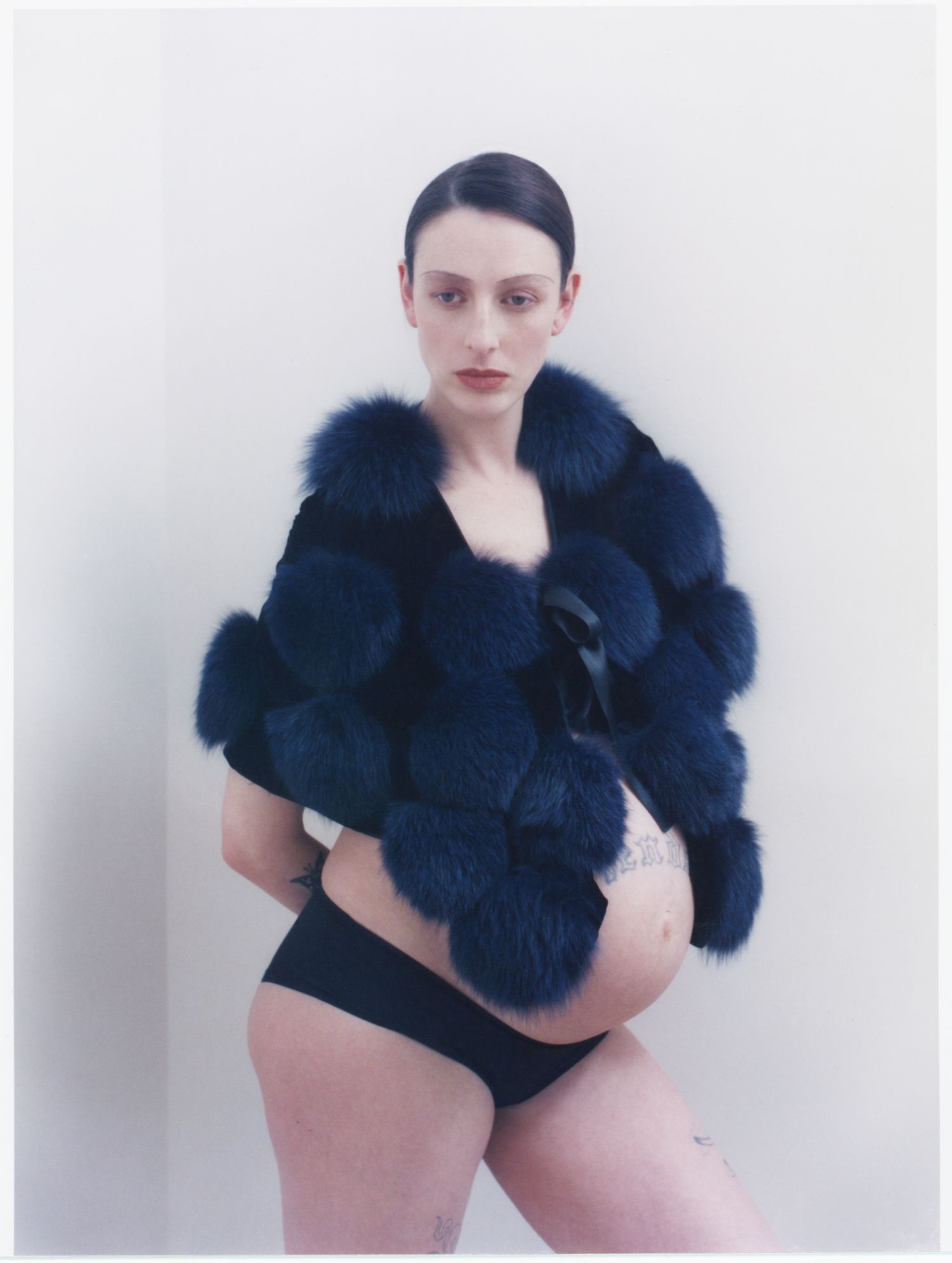 A pregnant model poses while wearing a vintage Giorgio Armani cape from HONNÊTE Boutique.