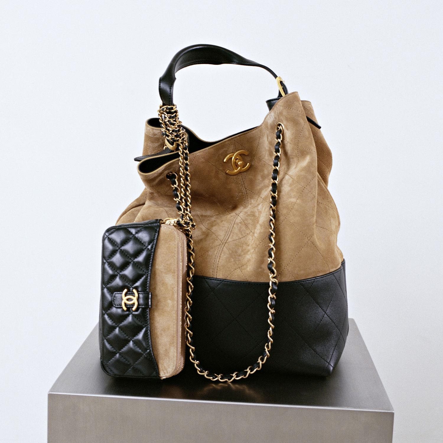 A still life of a two-tone shopping bag and wallet from Chanel Métiers d'arts 2024/2025 collection.