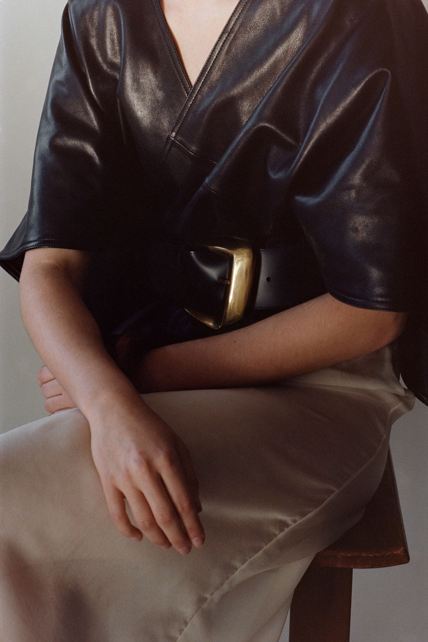 A close up of a black leather belt on a sitting model.