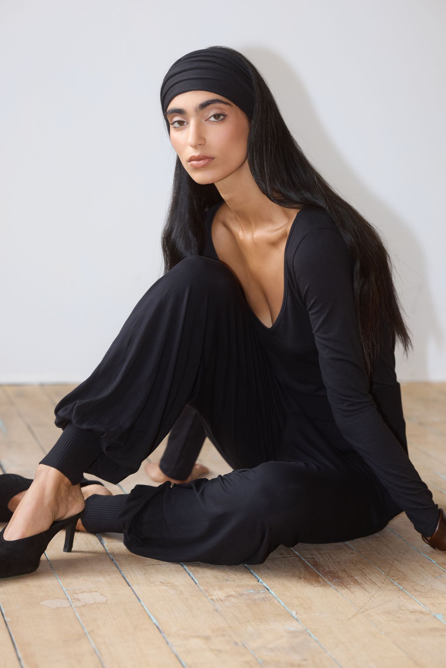 Model Amrit wears a black headband, black scoop tee, and knit pants from Waves of Hydra.