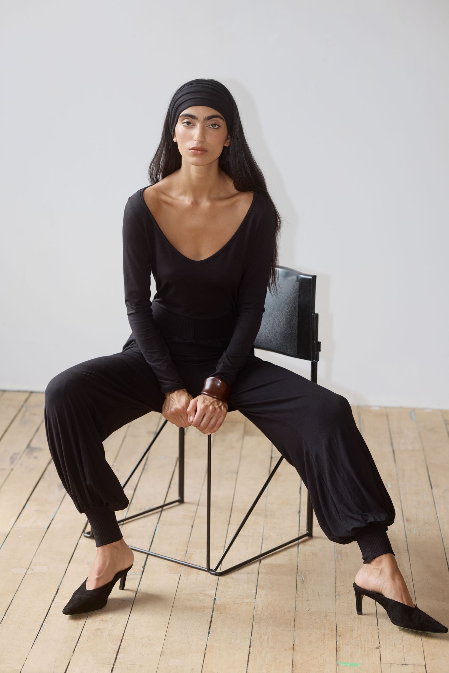 Model Amrit wears a black headband, black scoop tee, and knit pants from Waves of Hydra.