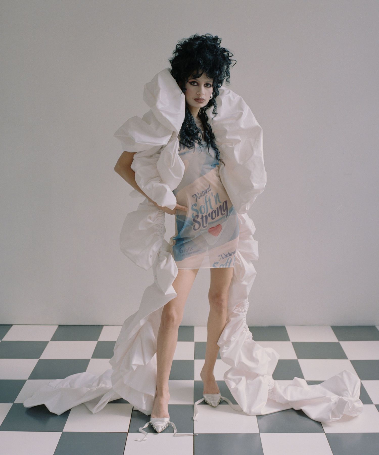Model Biba stands on a black-and-white checkboard tile floor wearing a dramatic boa and dress by a LaSalle college graduate.