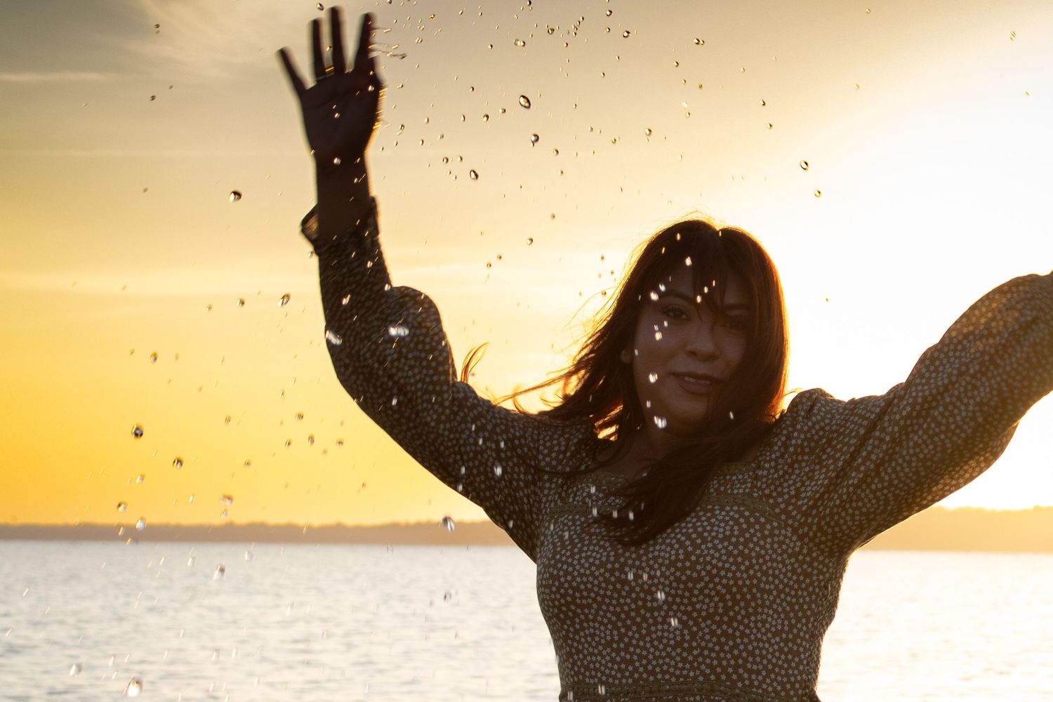 Woman celebrating by the water during a warm golden sunset in Waco, Texas
