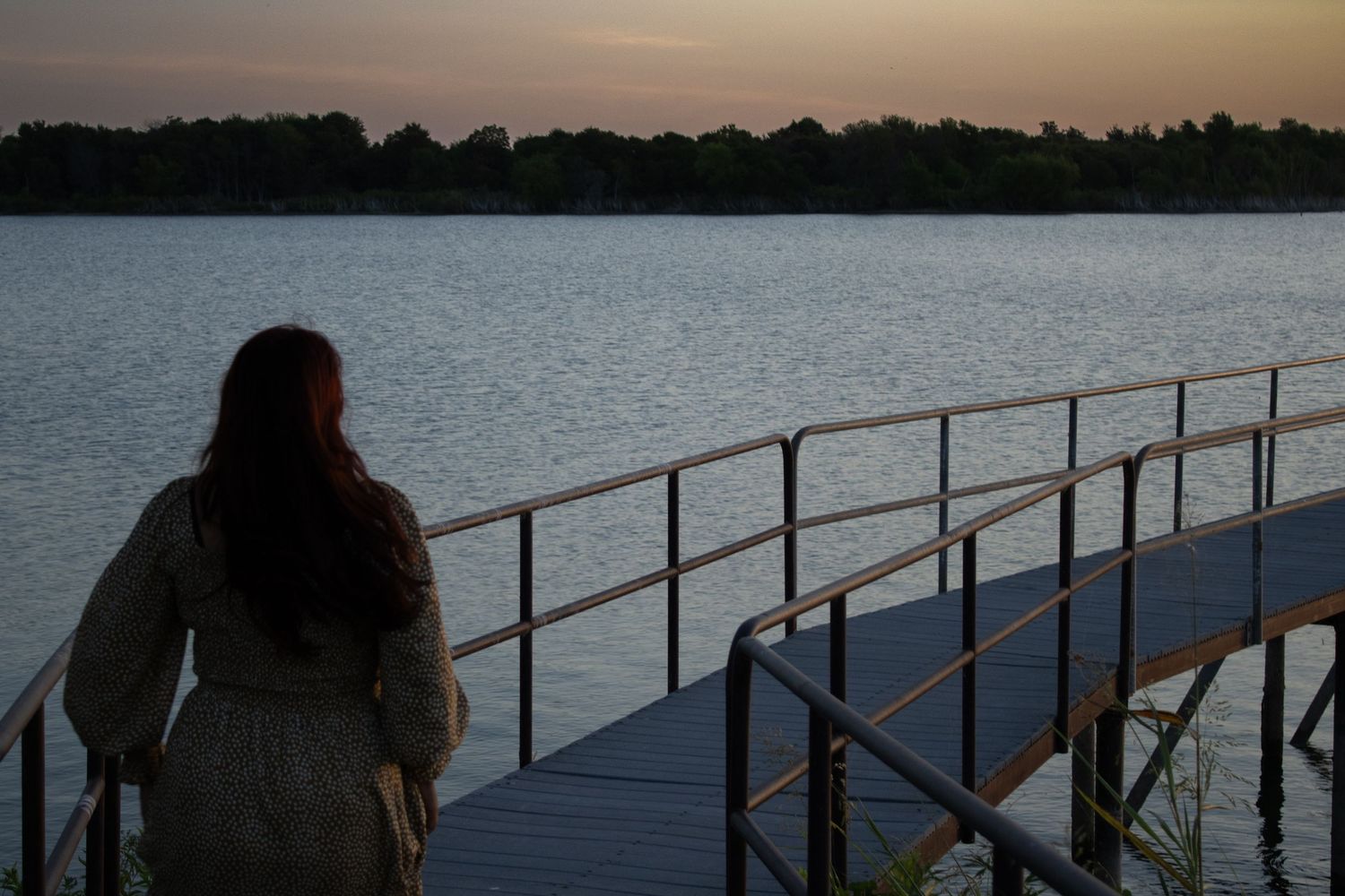 Woman walking along a dock beside the water at dusk