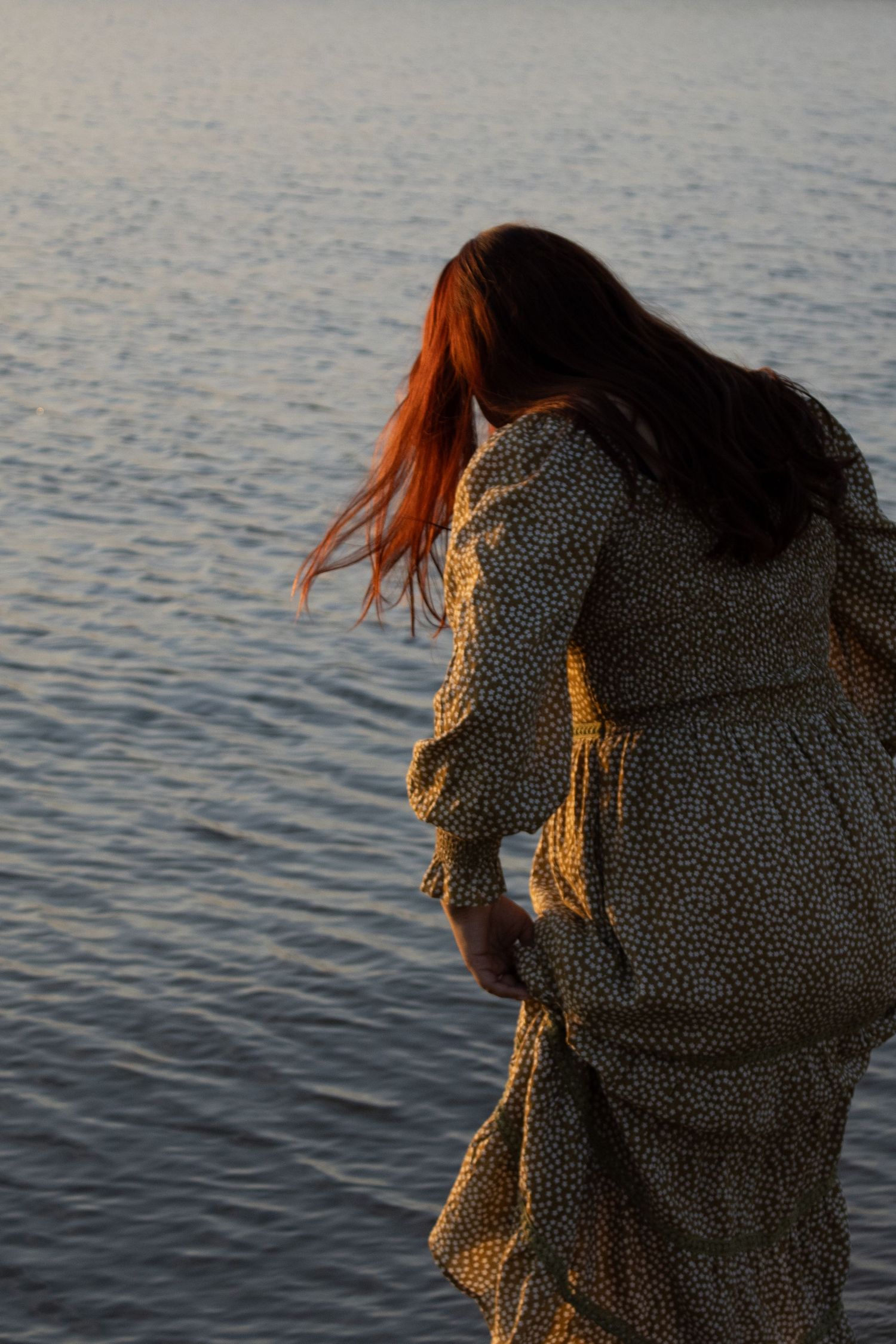 Woman standing beside the water during golden hour