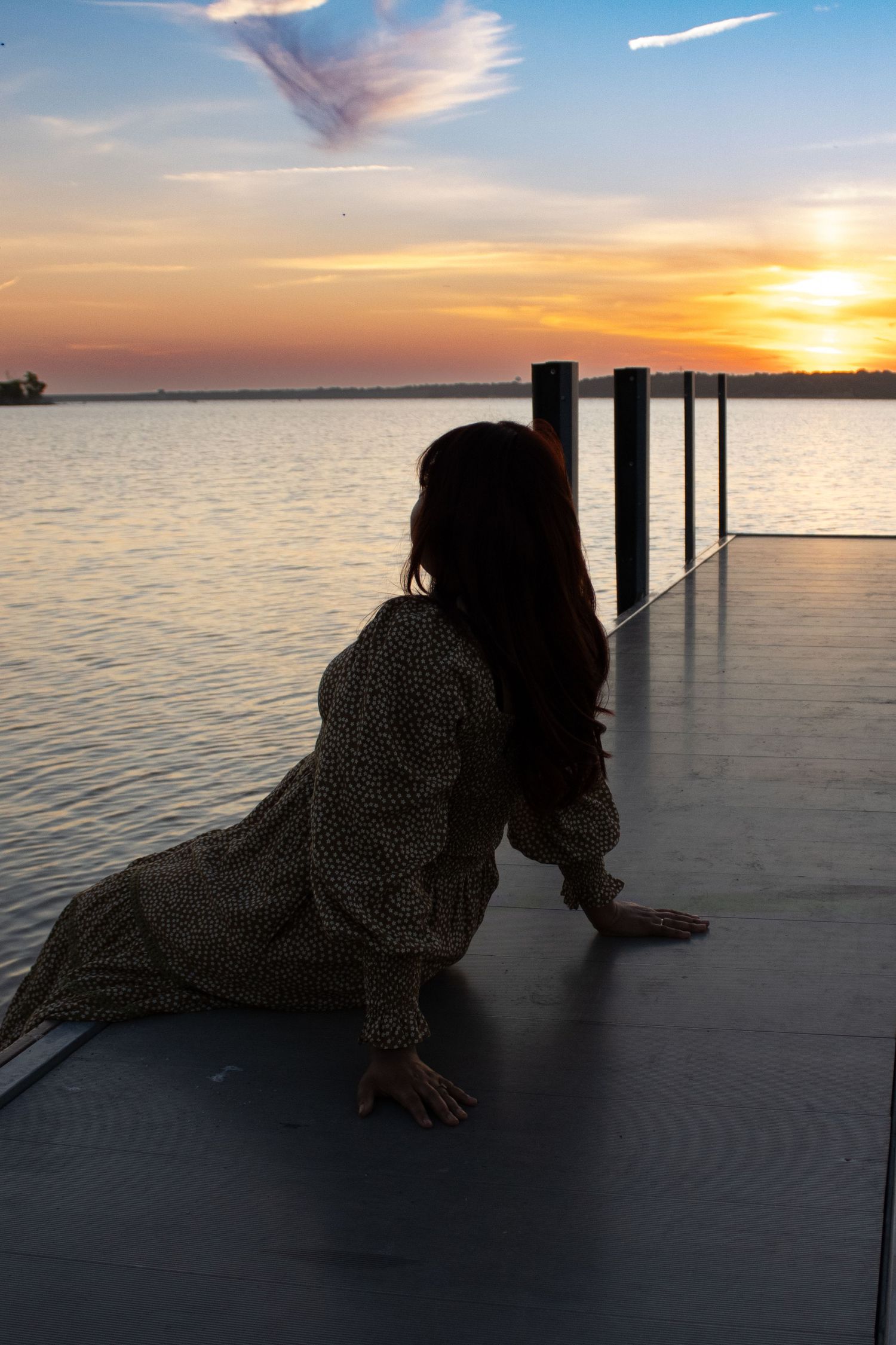 Woman sitting by the water watching the sunset