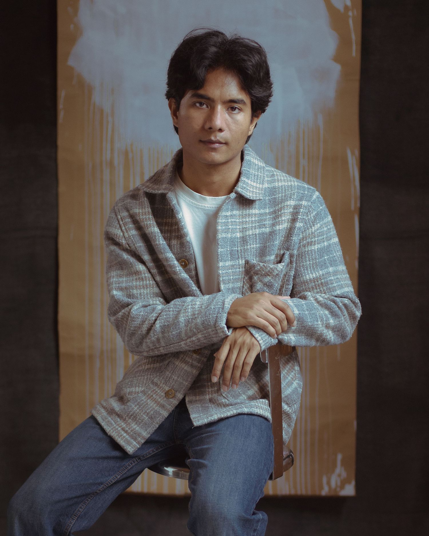 Man in his late 20's sitting with eyes looking in the camera in a studio