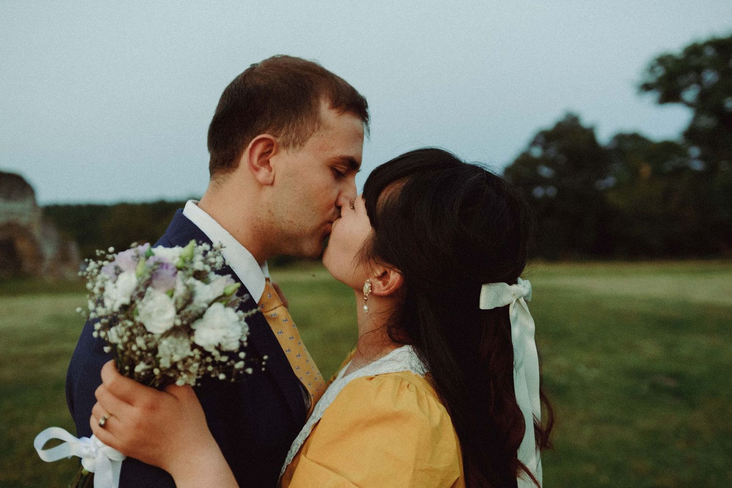 Newly wed Couple kissing in a field during a cinematic pre-wedding photoshoot