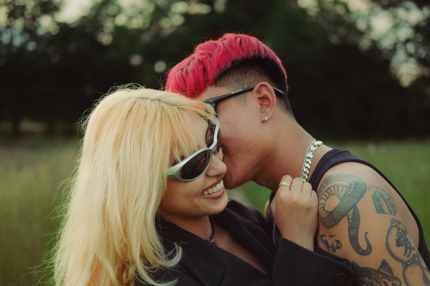 Two young couple teasing, romantic, man with tattoo and girl with sunglasses in a field.