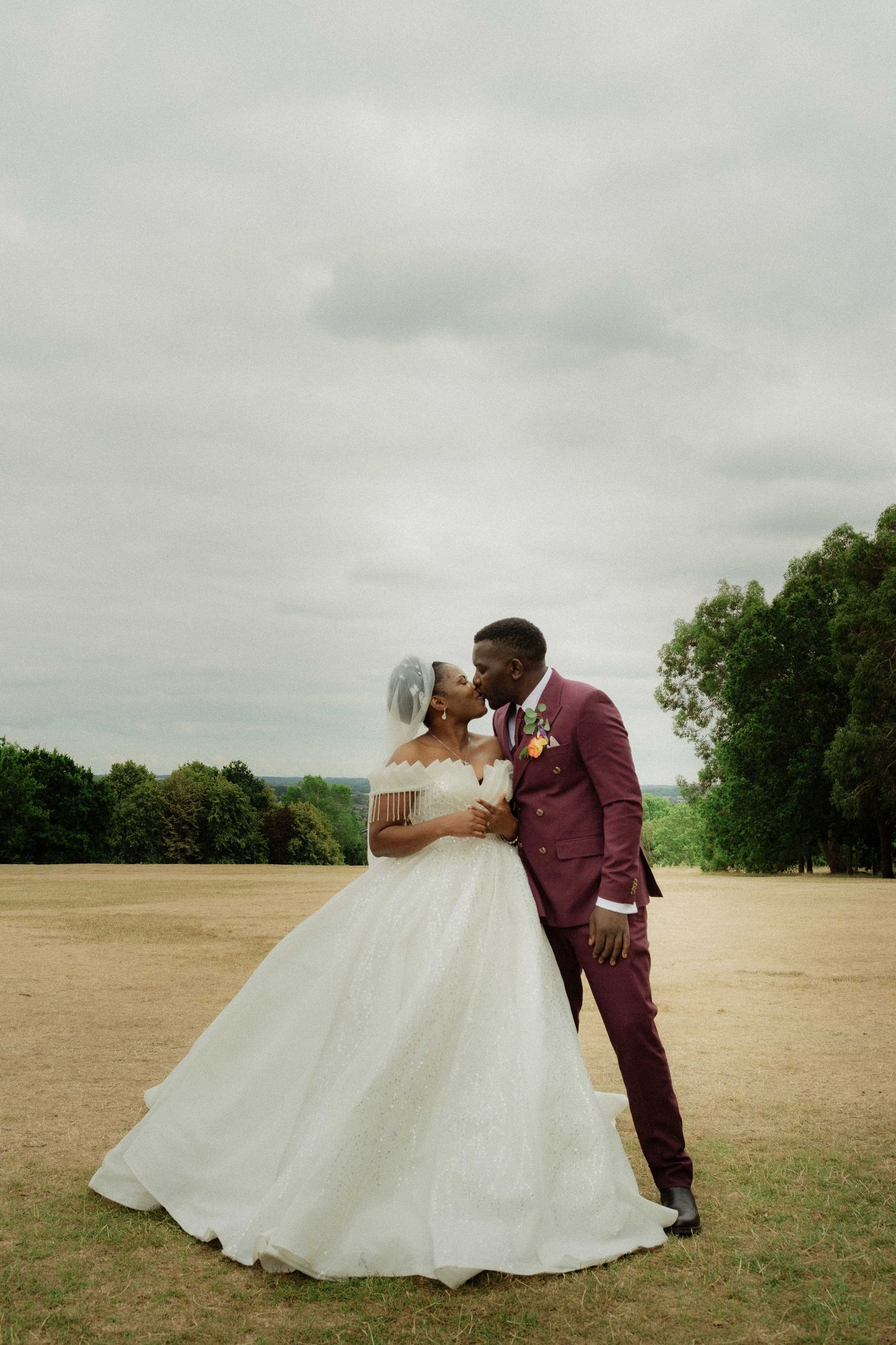 Newlywed couple embracing in an open field during a cinematic wedding photoshoot