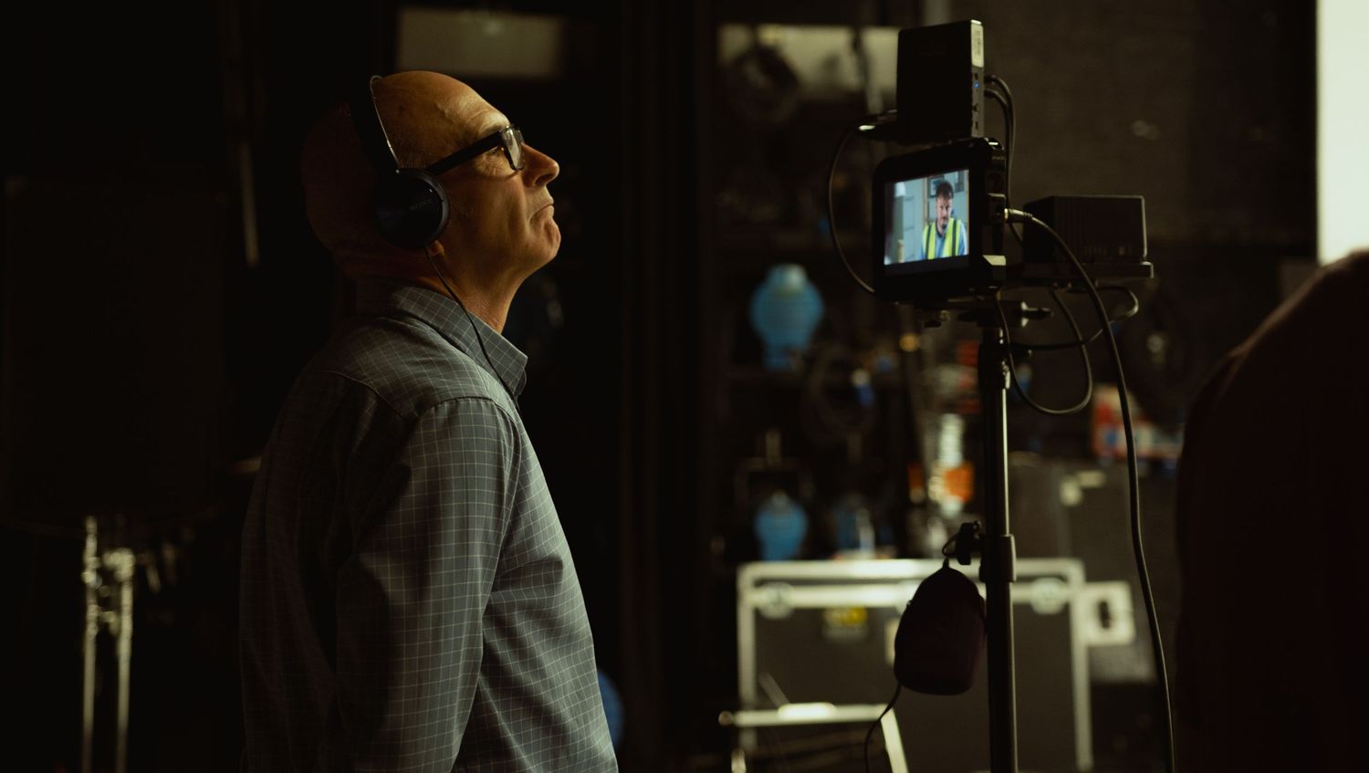 Behind-the-scenes photograph of a director working on a film set, looking at the monitor.