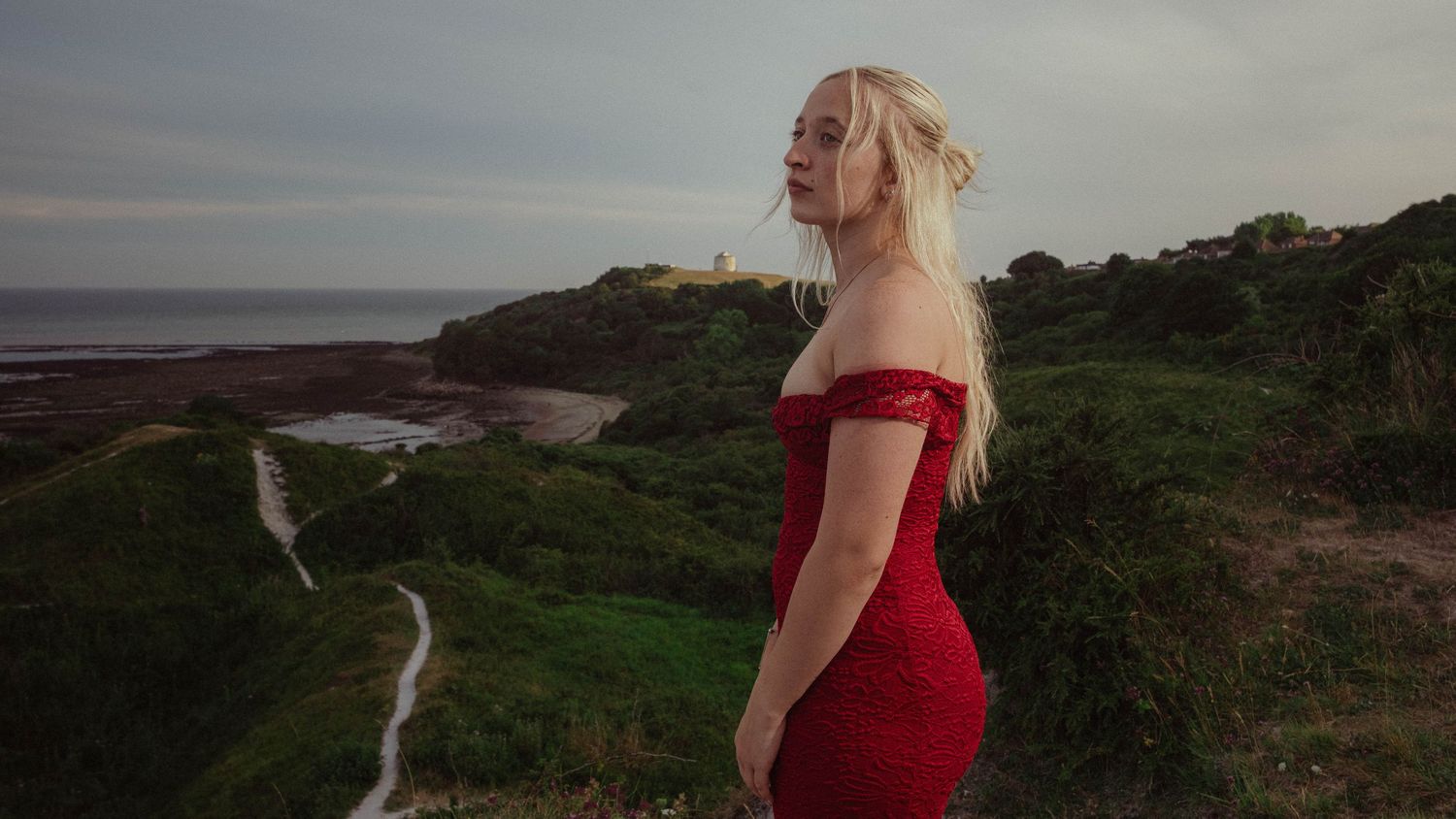 Cinematic portrait of a woman in a red dress overlooking the coast