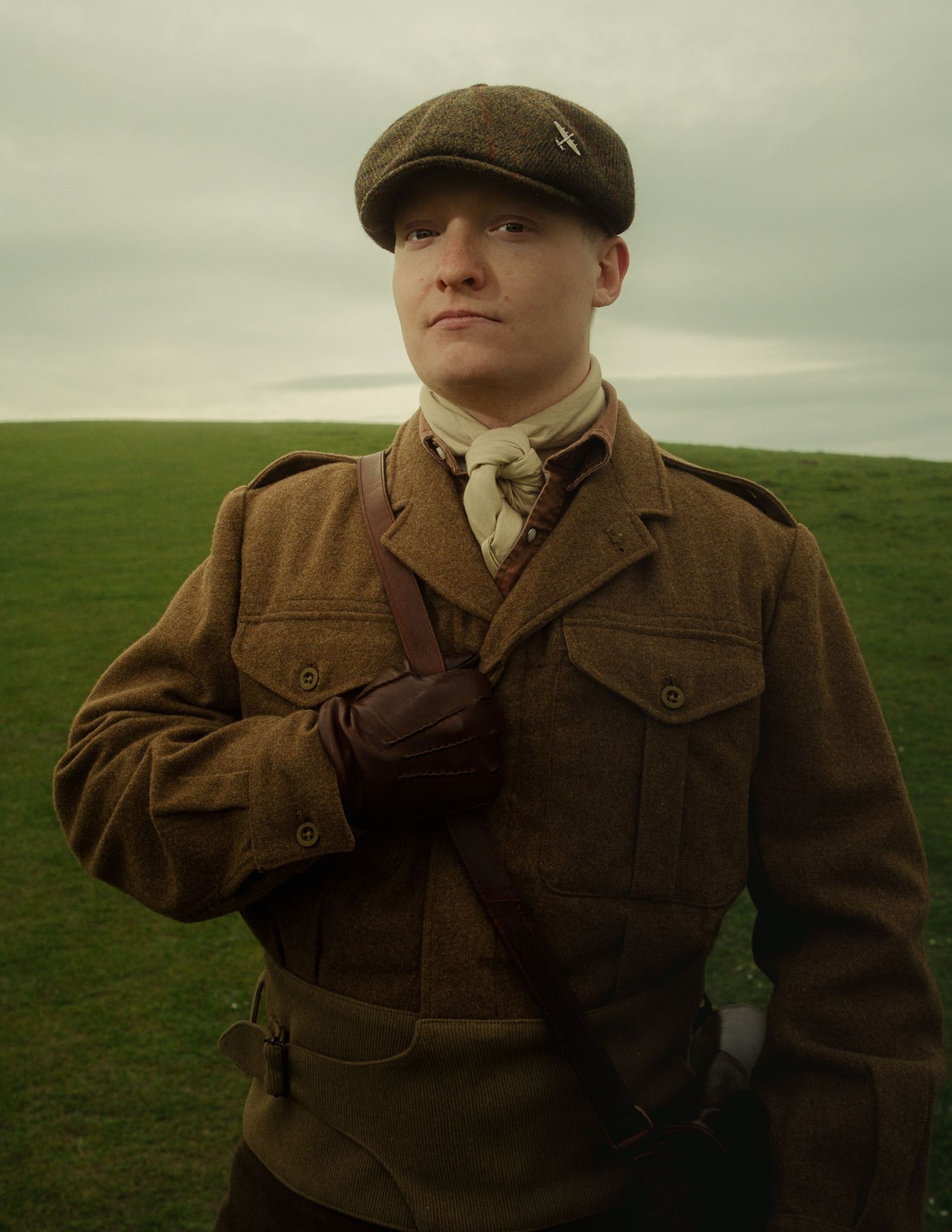 Cinematic portrait of a man in vintage military clothing standing in an open field