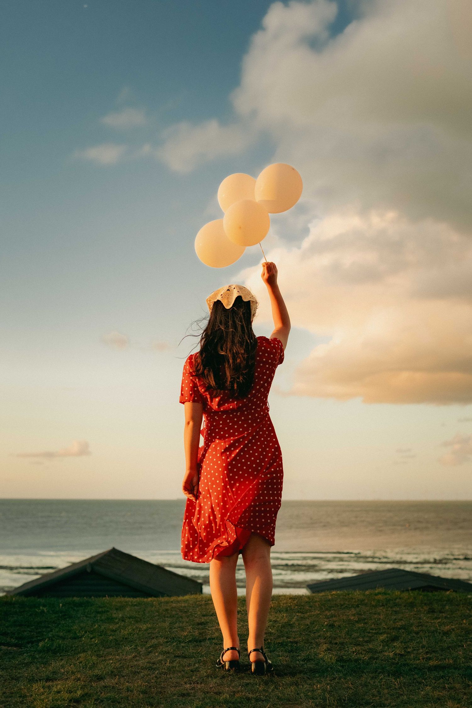 Cinematic portrait of a woman holding balloons by the coast at sunset