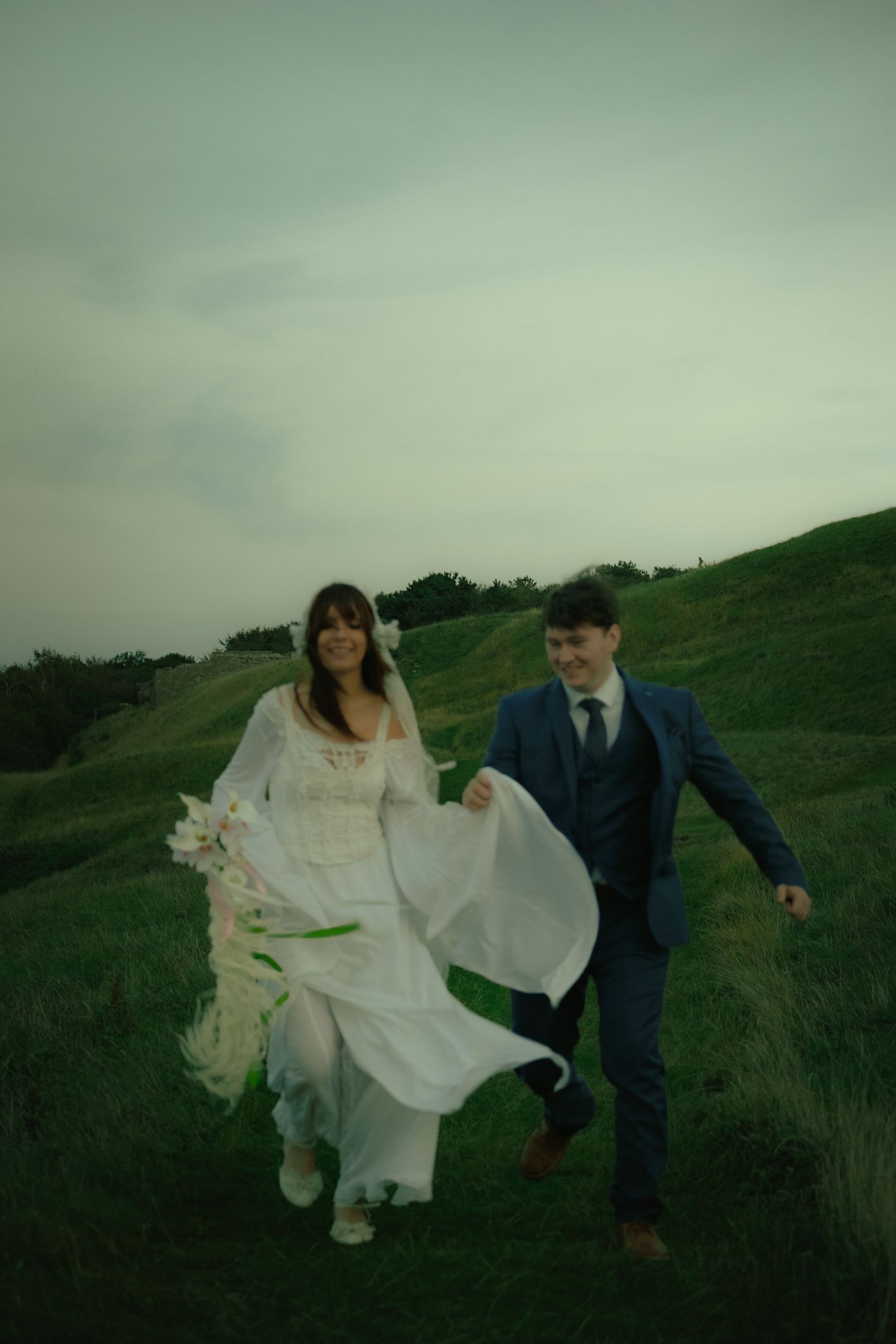 Newlywed couple running together through a field in a joyful cinematic wedding photograph