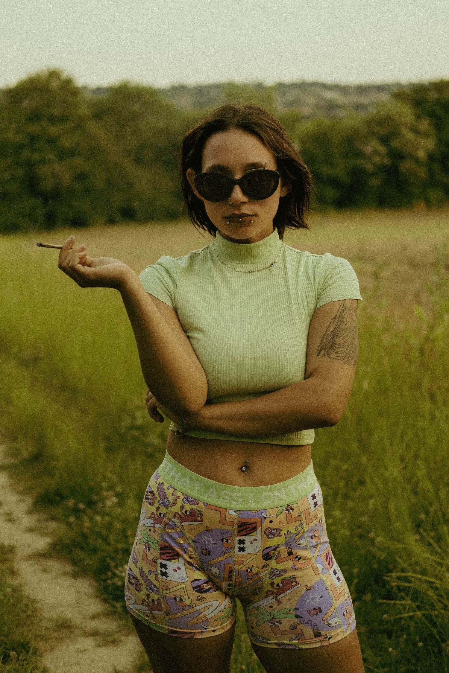 Outdoor fashion portrait of a woman wearing sunglasses in a field