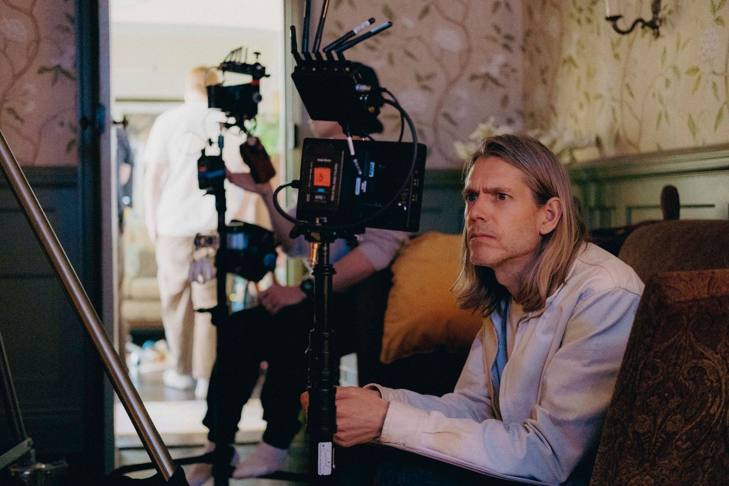 Behind-the-scenes photograph of a director looking at the monitor during a film production.