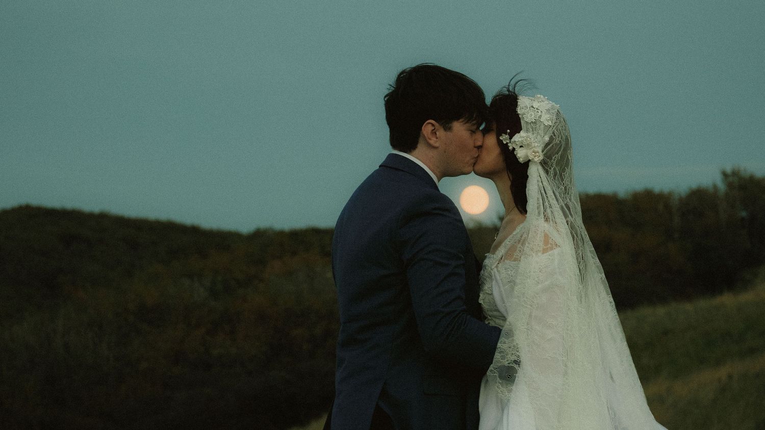 Newlywed couple sharing an intimate kiss outdoors during a wedding photoshoot
