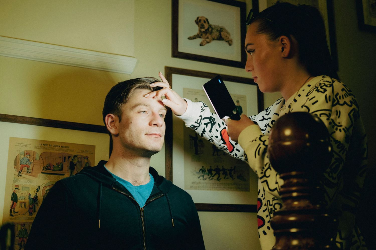 Behind-the-scenes photograph of a makeup artist preparing an actor on a film set.