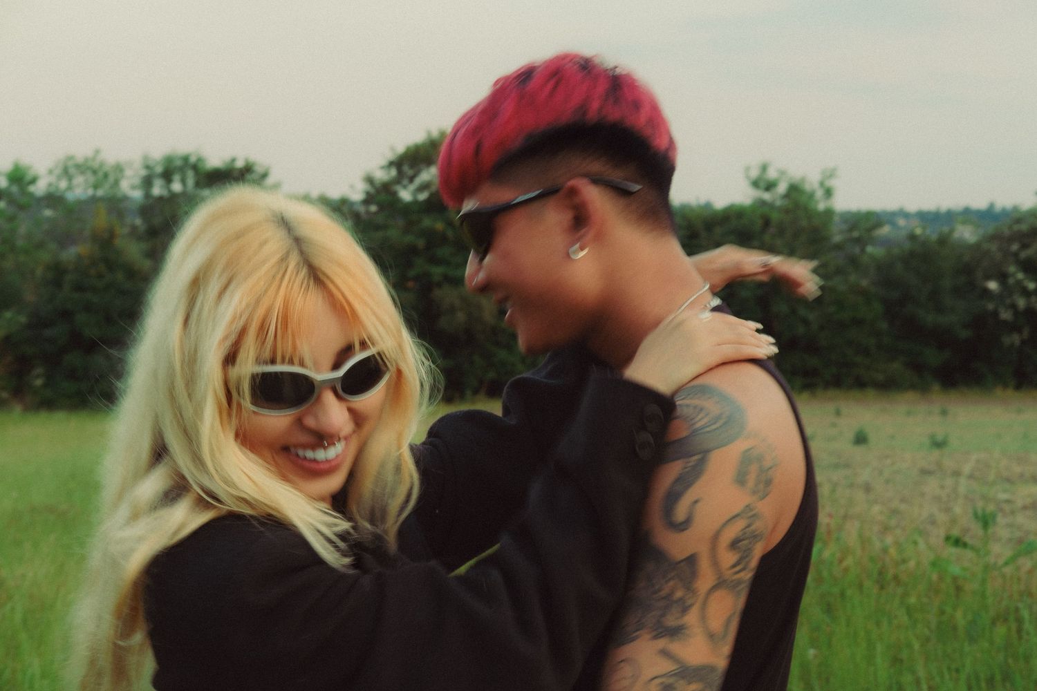 Candid couples portrait of a couple embracing outdoors in a field, capturing a warm and intimate moment.