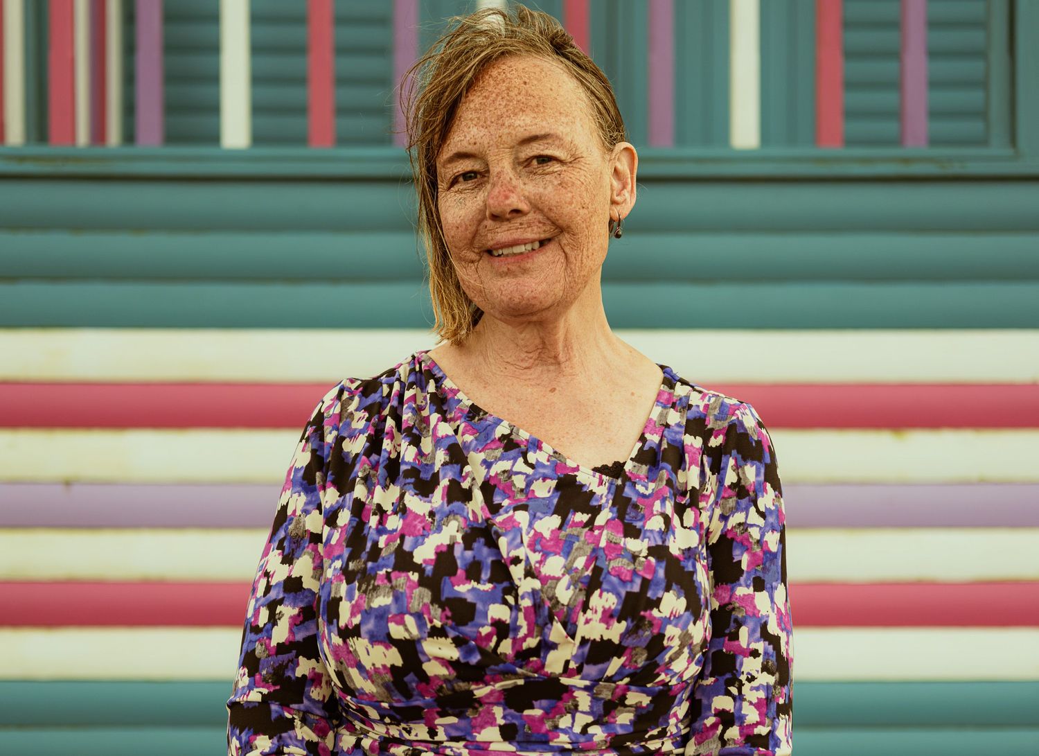 Environmental portrait of a woman photographed against a colourful architectural background