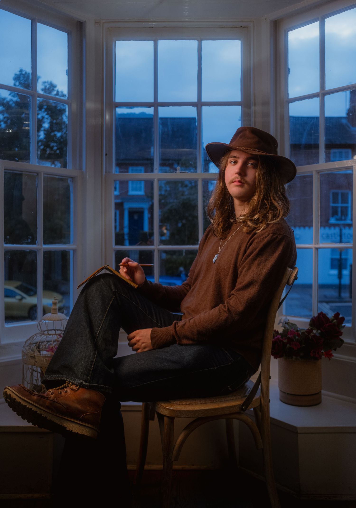 Cinematic portrait of a writer sitting beside a window in an intimate interior
