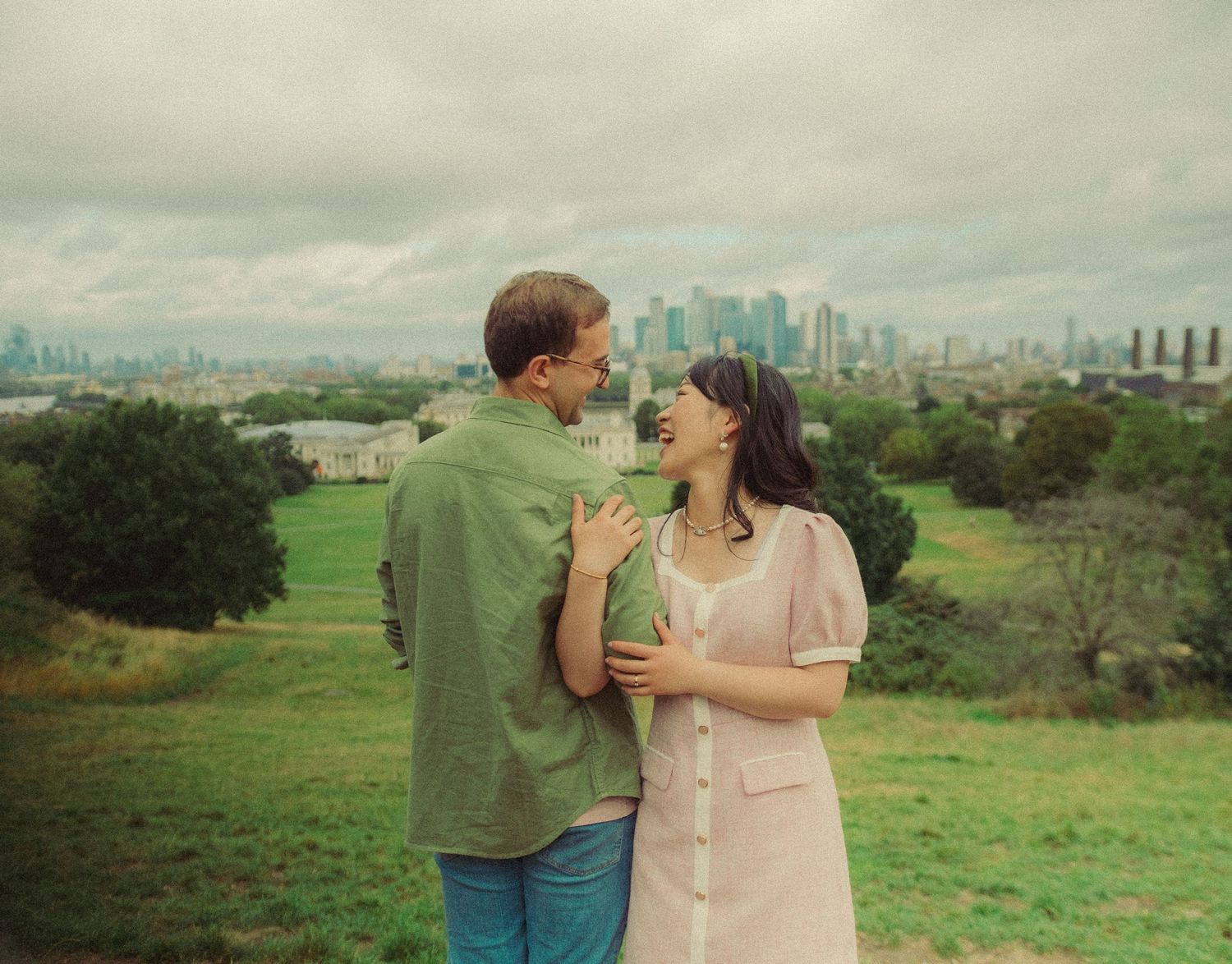 Romantic couples portrait of a couple embracing in a park with the London skyline in the distance.