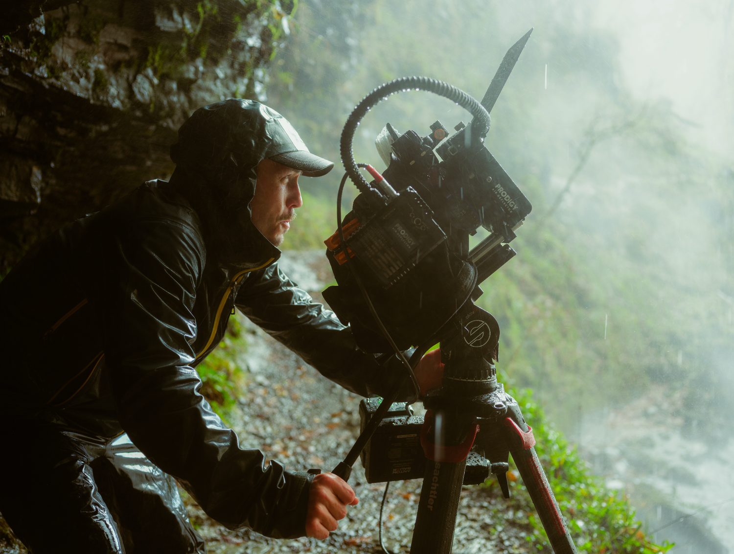 Behind-the-scenes photograph of a cinematographer filming a scene in a forest using professional cinema equipment.