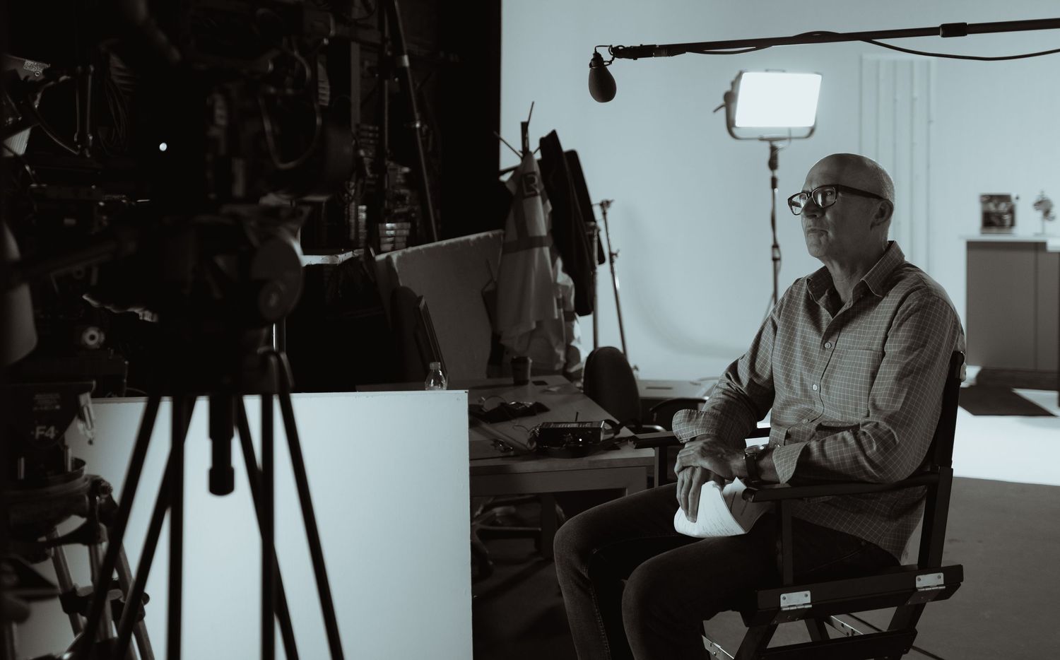 Black and white behind-the-scenes photograph of an interview being filmed on a professional film set.