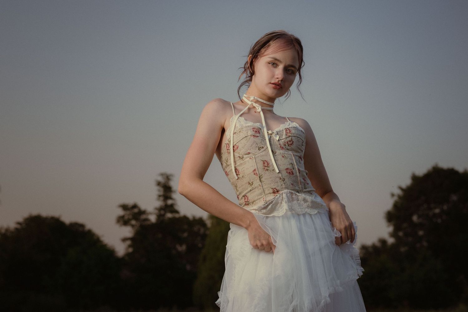 Cinematic portrait of a woman wearing a white dress outdoors at sunset